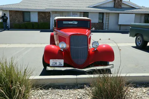 Bright red 1930s Ford hot rod parked in front of the parish hall
