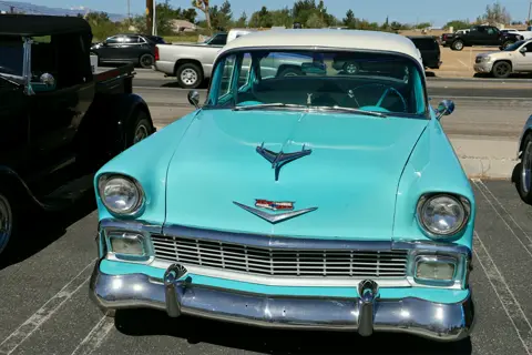 Turquoise and white 1956 Chevy Bel Air with its hood ornament gleaming in the sun