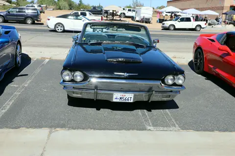Black Thunderbird convertible and red Corvette parked side by side