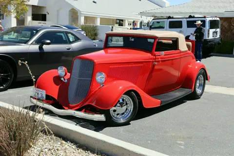 Red 1933 Ford roadster with tan convertible top outside the parish hall