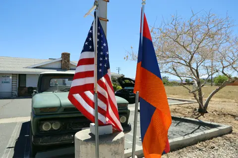 American and Armenian flags flying together over the car show