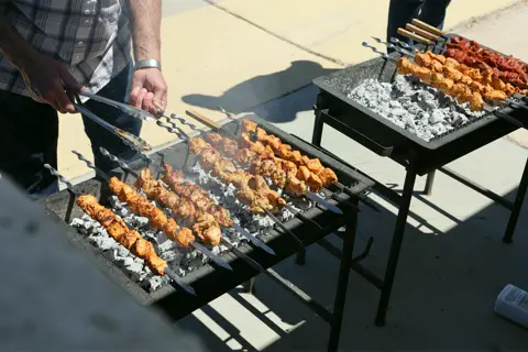 Chicken and pork kebab skewers grilling over glowing coals