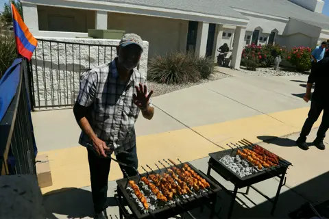 Volunteers turning rows of kebab skewers on the outdoor grills
