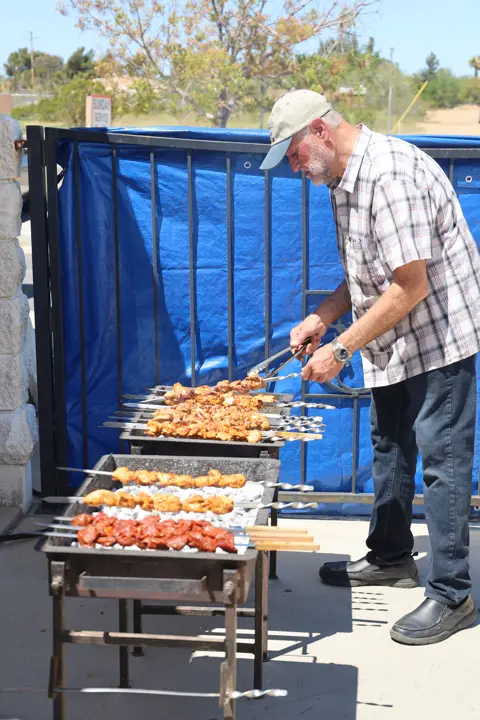 Grill master proudly leaning back with a full rack of kebab skewers