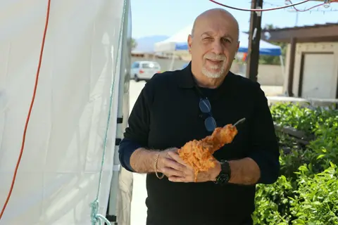 Smiling parishioner showing off a freshly grilled kebab skewer