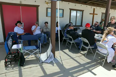 Guests seated in the shade of the patio during the car show gathering