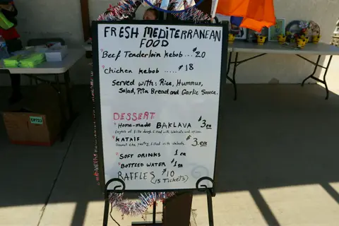 Handwritten menu board offering fresh Mediterranean food, kebab plates, and baklava