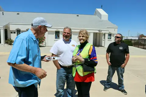 Organizers and volunteers in safety vests sharing a laugh between the cars