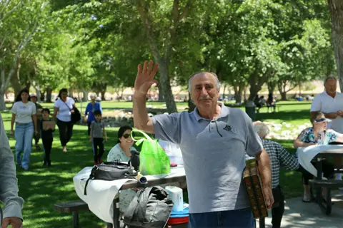 Parishioner waving hello across the picnic tables at the park