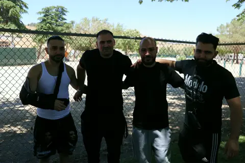 Young men of the parish arm in arm by the fence at the picnic