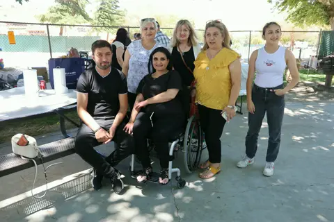 Friends and family gathered around a bench for a group photo at the picnic