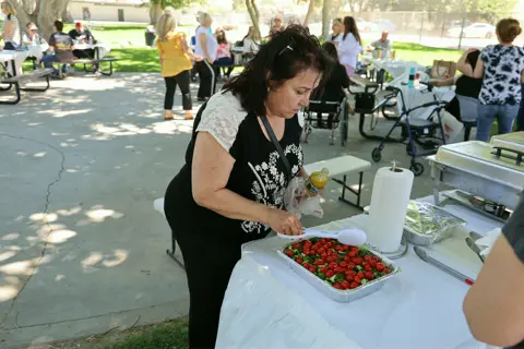 Volunteer arranging fresh strawberries on trays at the serving table