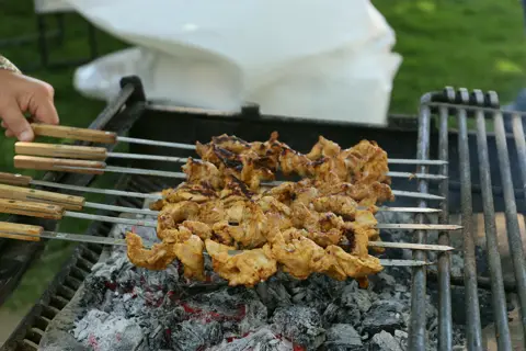 Close-up of marinated chicken kebab skewers cooking over charcoal
