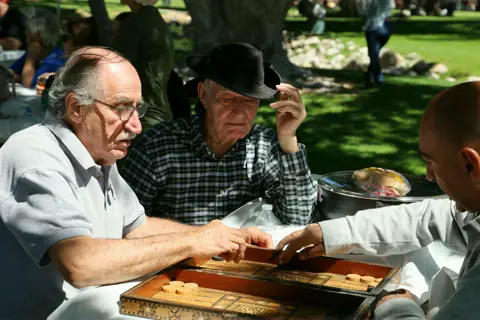 Elders deep in a backgammon match at the picnic table